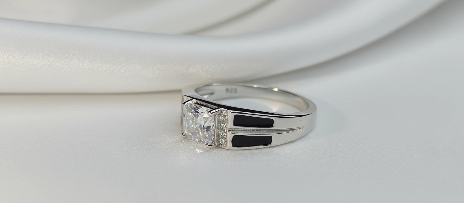 A modern men's 925 sterling silver ring featuring a large radiant-cut cubic zirconia, pavé side accents, and a bold band with black enamel inlay.