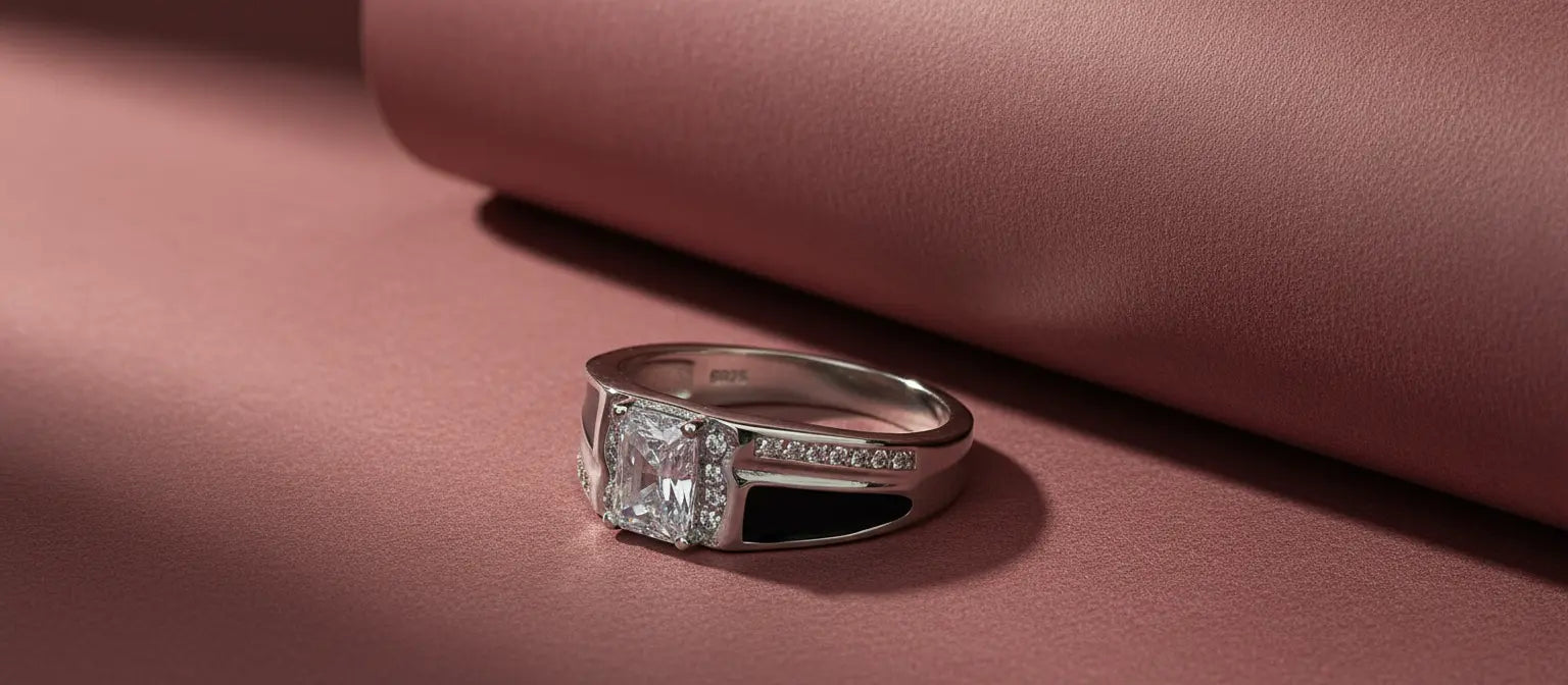 The Imperial Solitaire Ring in 925 sterling silver, featuring a large emerald-cut center stone, halo, and black enamel accents on a rose-colored background
