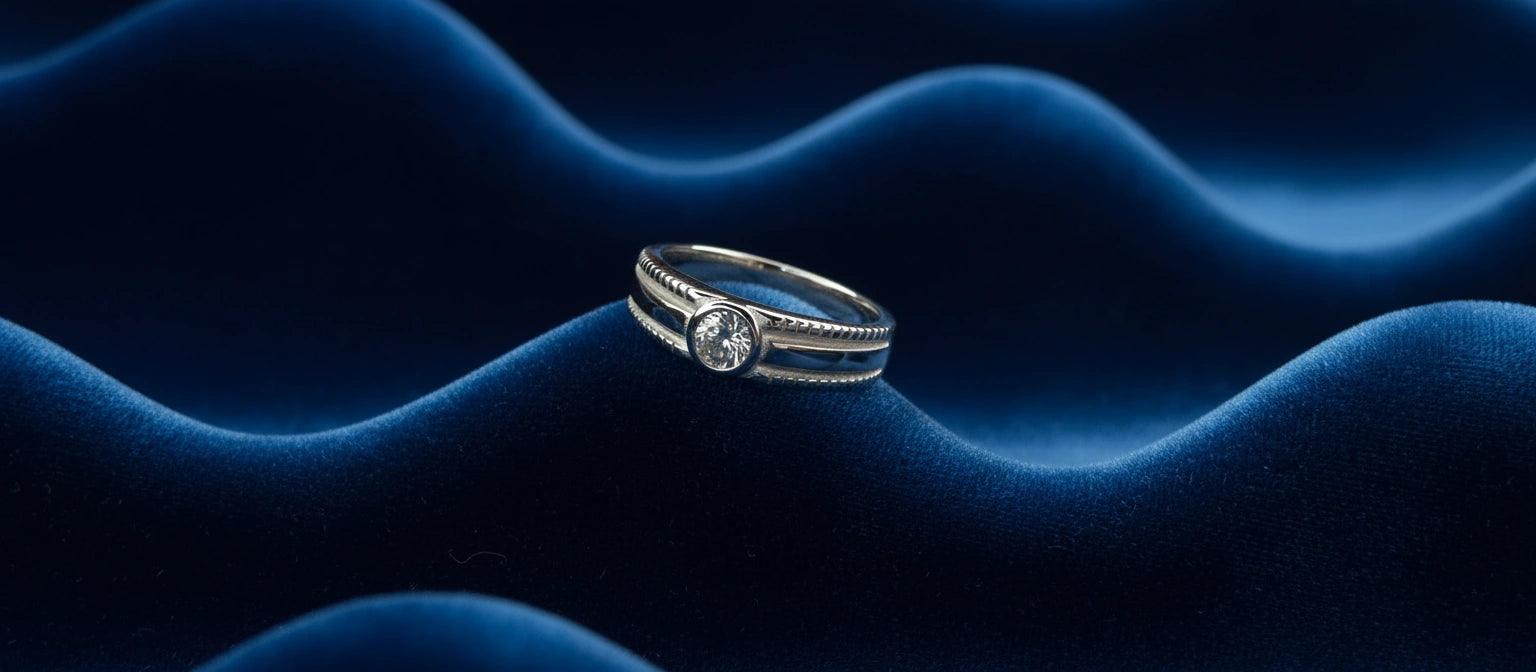 The Meridian Solitaire Ring by Narayan Jewellers, a 925 sterling silver split-shank ring with a bezel-set solitaire, on a radiating blue velvet surface.