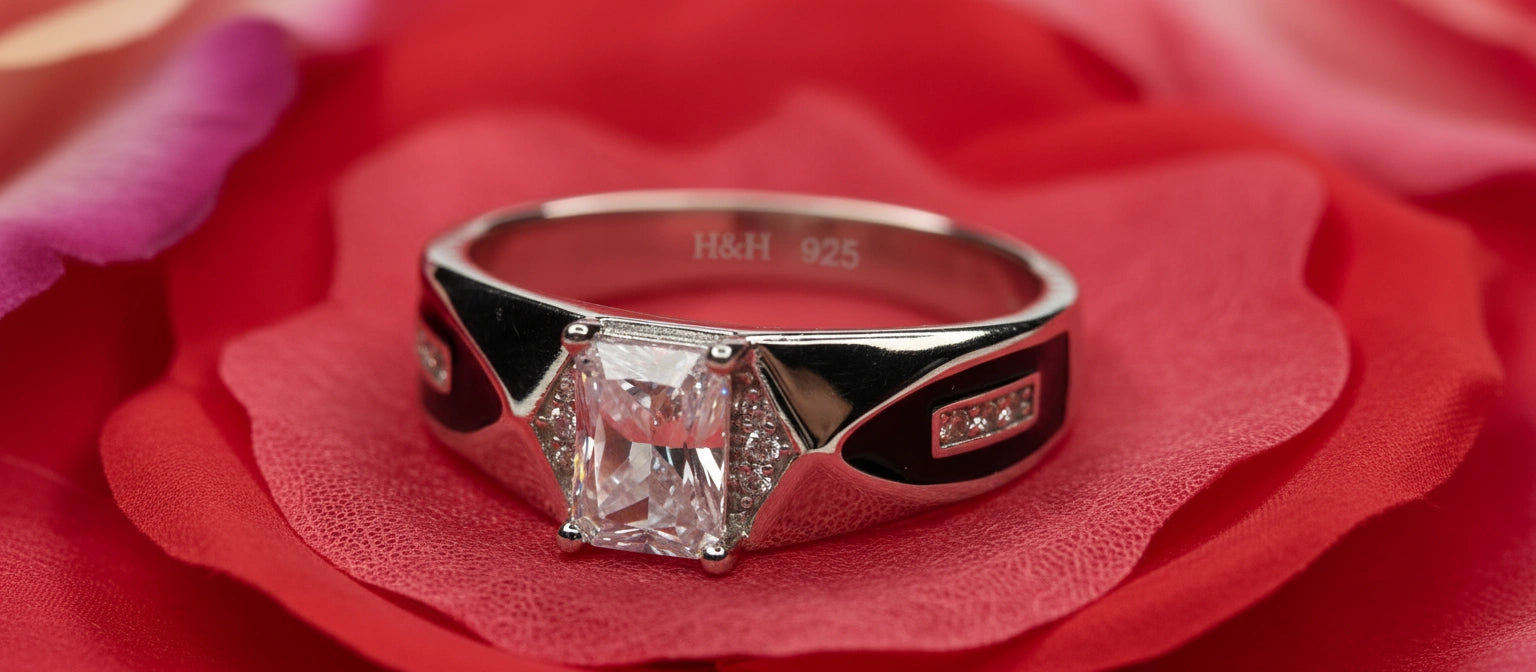 The Regent's Decree Ring by Narayan Jewellers, crafted in 925 silver with an emerald-cut solitaire and intricate black enamel details, resting on a red rose.