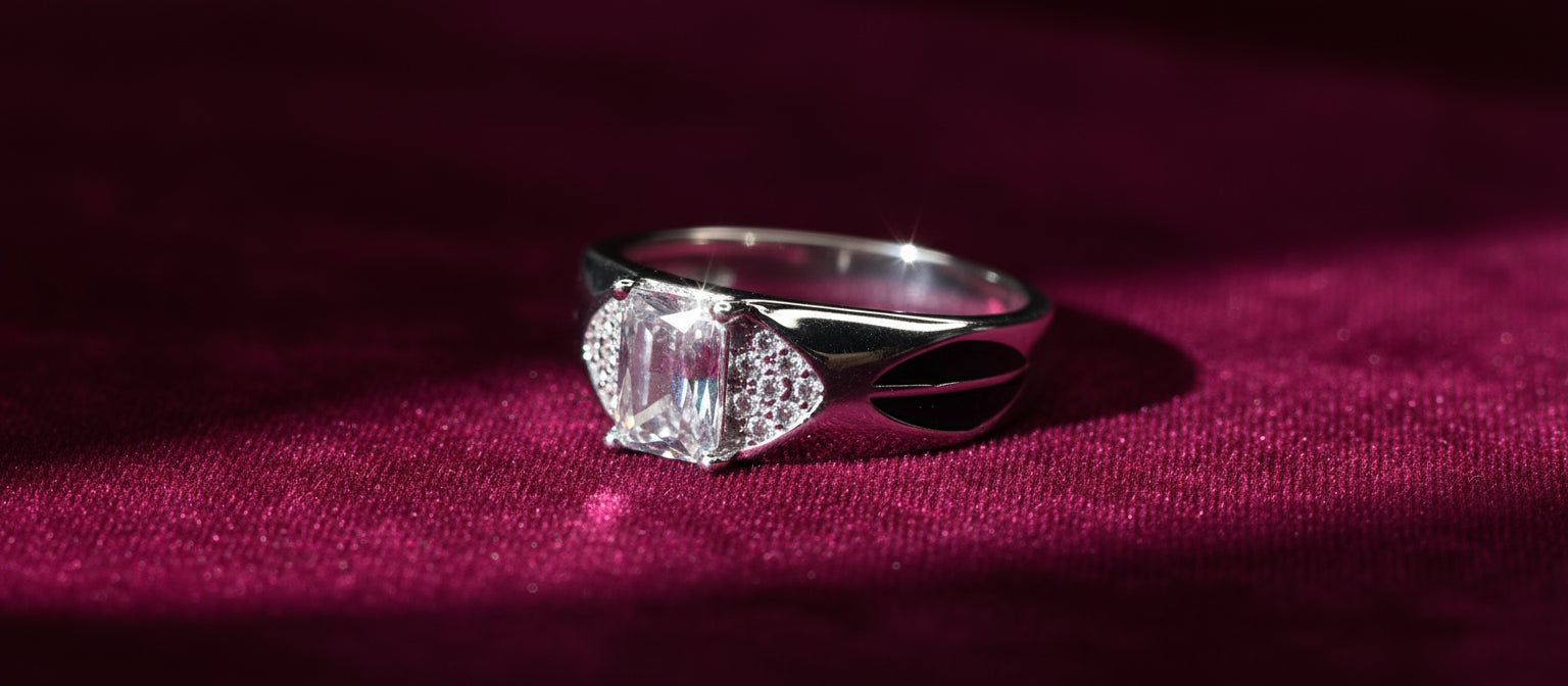 The Viceroy Solitaire Ring by Narayan Jewellers, crafted in 925 sterling silver with an emerald-cut stone and black enamel leaf details, on a rich magenta background.